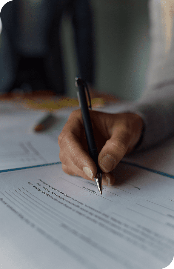 Hand writing on a document with pen ready to sign